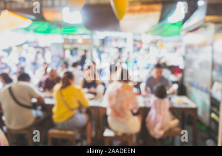 Abstract blurred image of people sitting around the table in local Asian street food shop in the fresh market. Stock Photo