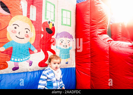 Girl with coat next to an inflatable castle, alone and sad. Stock Photo