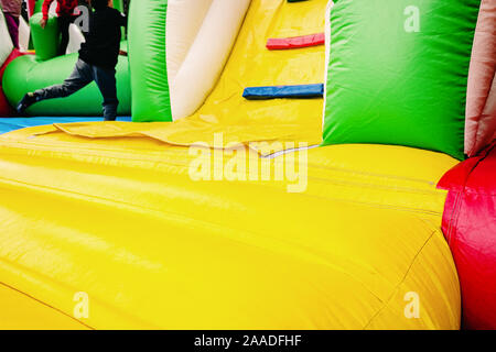 Detail of an inflatable castle of colorful rubber bands with some children jumping, copy space. Stock Photo