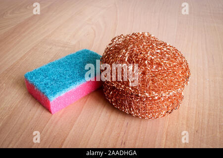 Kitchen sponge for dishes and a metal washcloth for complex dirt on a wooden background. Stock Photo