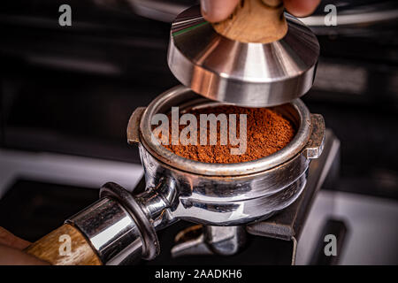 Barista is using a tamper to press freshly ground morning coffee Stock Photo