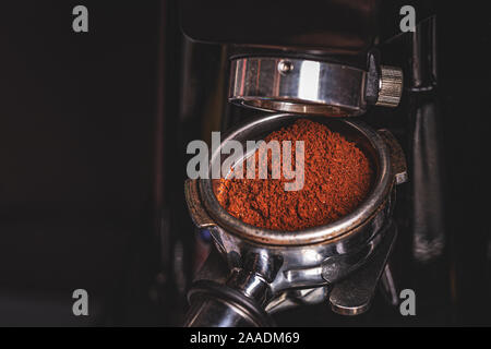 Grinding coffee on professional grinder machine in coffeeshop, close up Stock Photo