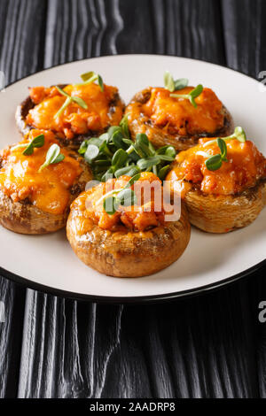 Mushrooms stuffed with minced meat and cheddar cheese close-up on a plate on the table. vertical Stock Photo