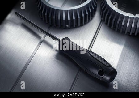 Professional reinforced black matt screw driver placed on a polished aluminum surface. View from the top. Stock Photo