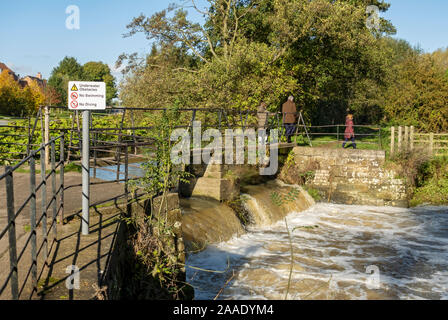 Walkers people crossing the footbridge over the old sluice gates of Thirsk Mill Thirsk North Yorkshire England UK United Kingdom GB Great Britain Stock Photo