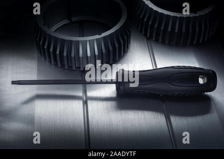 Professional reinforced black matt screw driver placed on a polished aluminum surface. View from the top. Stock Photo
