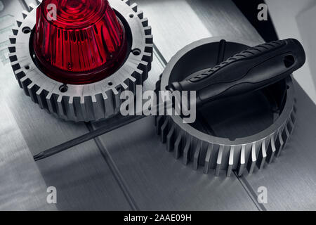 Professional reinforced black matt screw driver placed on a gearwheel. View from the top. Stock Photo