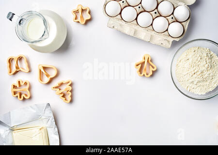 Objects and ingredients for baking, plastic molds for cookies on a white background. Flour, eggs, milk, butter, cream. Top view, space for text Stock Photo