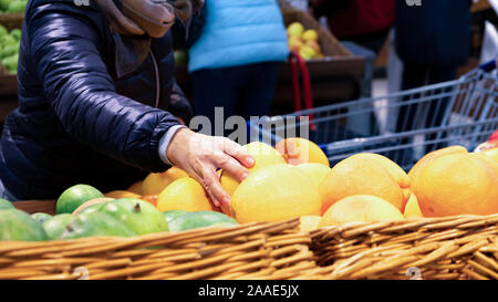 On the counter of the store fruit. A woman chooses a grapefruit. C. Trade food supermarket. Organic vegetables. Fresh ripe foods. Health Stock Photo