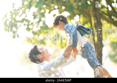 Cute Little Asian Boy In Adult Clothes Sitting On Beanbag Against Green 