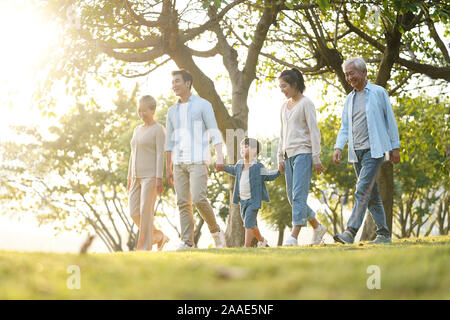 three generation happy asian family walking outdoors in park Stock Photo