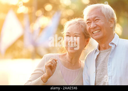senior asian couple enjoying good time outdoors in park at dusk, happy and smiling Stock Photo