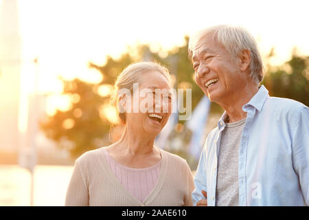 senior asian couple enjoying good time outdoors in park at dusk, happy and smiling Stock Photo