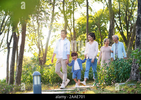 happy three generation asian family with mother father son grandmother, grandfather walking relaxing outdoors in park Stock Photo