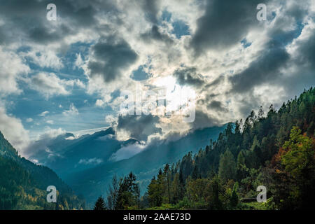 The sun breaking through the clouds over the Cordevole valley in the italian Dolomites on a sunny autumn day Stock Photo