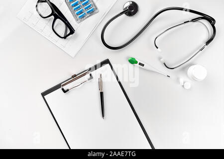 Stethoscope in the office of doctors.Top view of doctor's desk table, blank paper on clipboard with pen. Copy space. Designer's blank Stock Photo