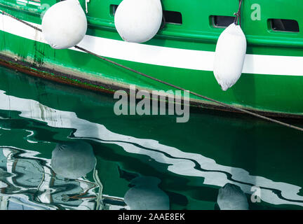 Green boat reflected in water. Stock Photo