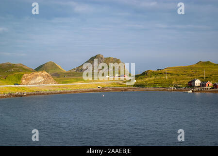 Summer view of a small fishing village with traditional, colorful wooden houses  and a road between green hills above the arctic circle in Finnmark. Stock Photo
