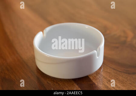 Close up, selective focus, shallow depth of view. Round glass ashtray isolated on wooden background . Clean empty round glass ashtray on an old wooden Stock Photo