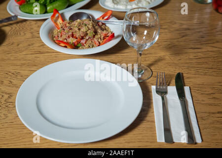 Table setting on wooden table . Dinner place setting. A white plate with silver fork and Wine glasses isolated on wood table. top view . Set of a dish Stock Photo