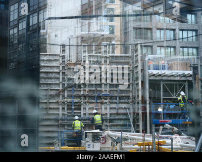 View through a window in a solid board of a large building site in London SW1 where construction workers prepare the shutters for concreting walls. Stock Photo