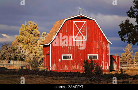 An old red wooden barn on a farm near Tumalo, Oregon, sits beneath a stormy winter sky. Stock Photo