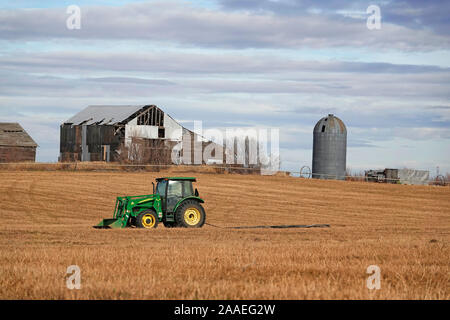 An old farm tractor sits in a field of already harvested alfalfa in the farm country near Madras, Oregon. Stock Photo