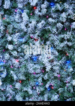 Christmas decoration with green pine leaves, white snow and blue, pink and purple  lights seen in  London, UK in the end of November 2019. Stock Photo