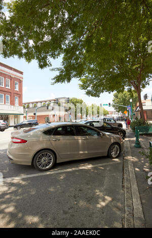 cars parked diagonally under tree shading at an angle on jackson street in city of dublin georgia usa Stock Photo