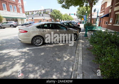 cars parked diagonally under tree shading at an angle on jackson street in city of dublin georgia usa Stock Photo