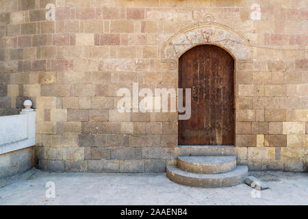External vaulted grunge closed wooden door in bricks stone wall, public historic Amir Aqsunqur Mosque, Blue Mosque, Cairo, Egypt Stock Photo