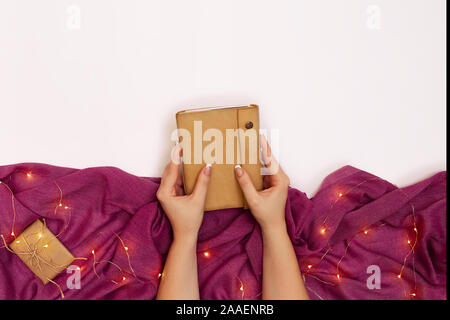 Woman's hands holding notebook in leather cover over white table Stock Photo