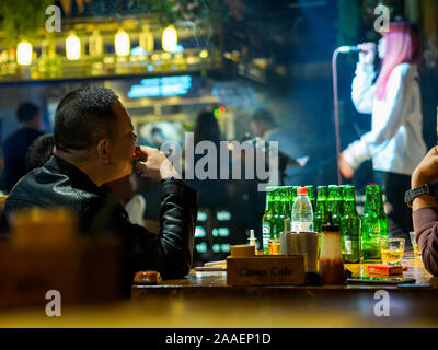 TIANJIN, CHINA - 5 OCT 2019 - A man drinks and smokes at a live music bar in Tianjin, China. Nightlife and entertainment theme. Stock Photo