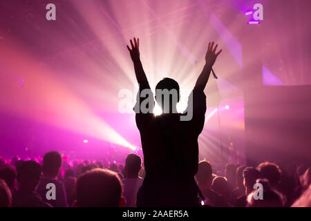 Silhouette of a Woman Dancing Whilst Sat On Someones Shoulders at a Music Concert with Bright Magenta Lighting Stock Photo