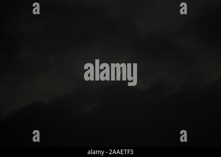 thin moon hiding behind clouds Stock Photo