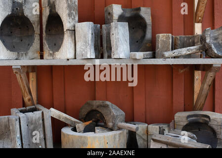 Old tools and forms for glass blowering on a shelf on a red rustic wooden wall Stock Photo