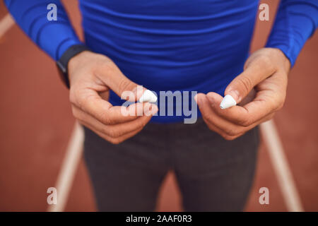 Hands of a male athlete in headphones at a stadium in the fog. Healthy lifestyle concept.