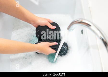Female hands washing black clothes in basin Stock Photo