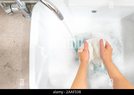 Female hands washing color clothes in sink with copy space Stock Photo