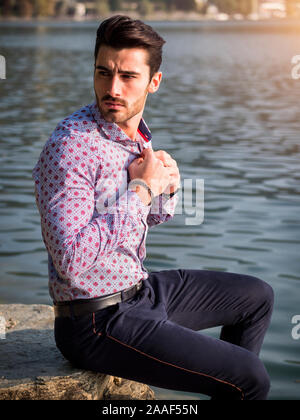 Young man wearing beside picturesque river or lake