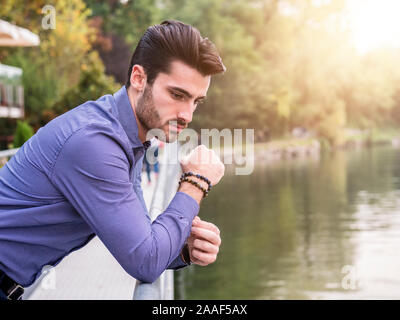 Young man wearing beside picturesque river or lake Stock Photo
