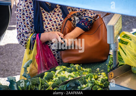 Close up view of an old woman paying by cash a seller in farmers market in Katerini. Scenic view of a typical day in farmers market in Katerini city, Stock Photo