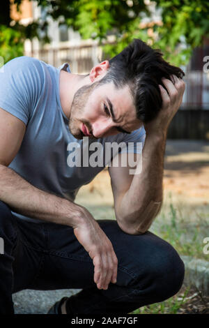 Depressed young man scratching his head, looking up Stock Photo