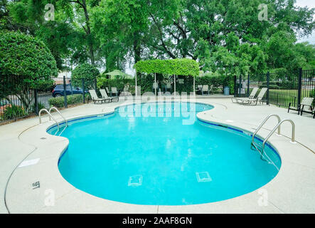 The swimming pool features an outdoor seating area with a covered pergola at Robinwood Apartments in Mobile, Alabama. Stock Photo