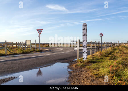 The causeway onto Mersea Island known as The Strood is covered by seawater twice a day. In the foreground a depth marker can be seen. Stock Photo