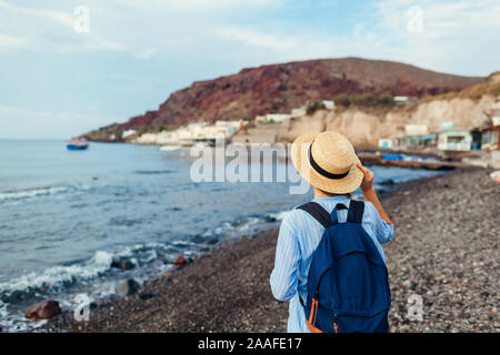 Woman traveler walking on Vlychada beach in Akrotiri on Santorini island, Greece. Tourist admiring sea landscape Stock Photo