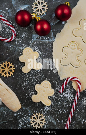 Overhead flat lay concept for baking Christmas cookies with rolled out cookie dough, cookies in the shape of happy gingerbread men ans seasonal decora Stock Photo