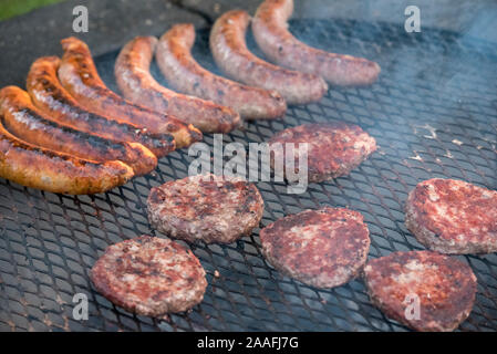 Hamburger patties and sausages being cooked over an open grill Stock Photo