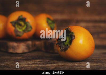 Fresh ripe persimmons on rustic wooden table. Copy space. Healthy organic fruits. Stock Photo