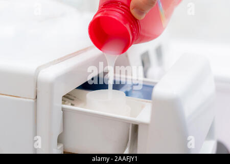 pouring the washing conditioner in the washing machine to get clean cloth Stock Photo